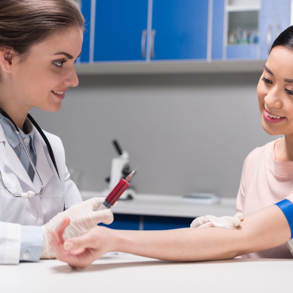young doctor taking blood sample from patient at laboratory